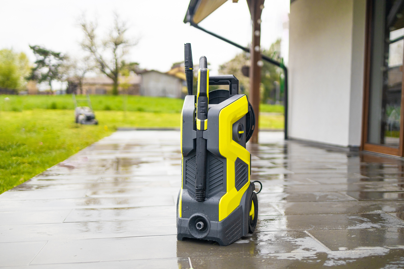 Pressure washer cleaning machine on wet concrete floor near the house build, cleaning terrace with a power washer